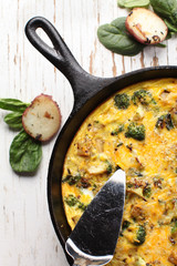 Baked egg frittata with spinach, cheese, broccoli, red potatoes, bacon, milk, and spinach top view