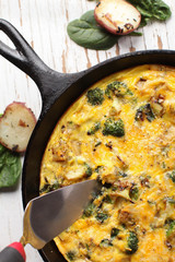 Baked egg frittata with spinach, cheese, broccoli, red potatoes, bacon, milk, and spinach top view with slice