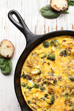 Baked egg frittata with spinach, cheese, broccoli, red potatoes, bacon, milk, and spinach top vertical view