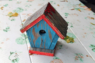 Weathered Wooden Birdhouse with Peeling Red and Blue Paint