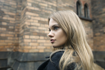 Naklejka premium close up outdoor portrait of attractive young blonde female on brick wall background