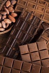 Dark homemade chocolate bars and cocoa pod on wooden
