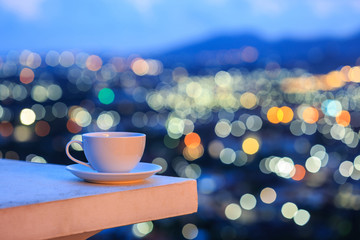 White coffee cup on counter and colorful blur light bokeh of cit