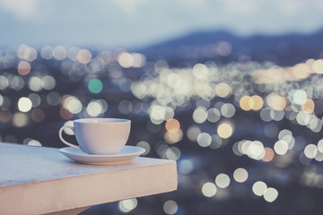 White coffee cup on counter and colorful blur light bokeh of cit