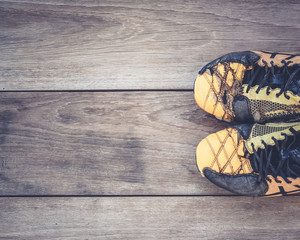 Old football shoes on grey wooden plank