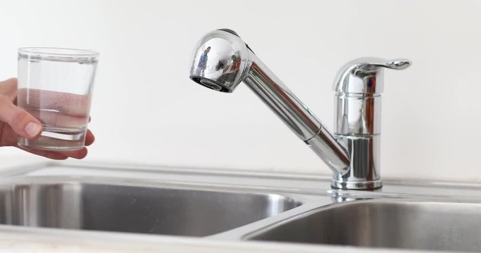 Woman collects water from the tap.