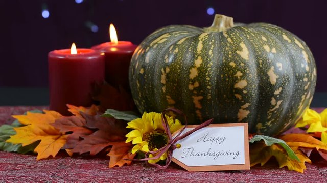 Happy Thanksgiving pumpkin centerpiece with candles against a bokeh fairy lights background, close up static.