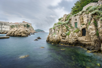 The stark walls, clear water and colorful doorways that line the beautiful Kolorina Bay in Dubrovnik, Croatia.