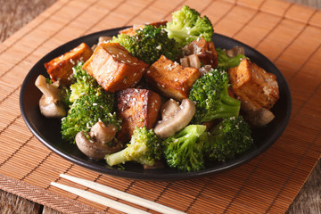 Fried tofu cheese with broccoli, mushrooms and teriyaki sauce close-up. Horizontal
