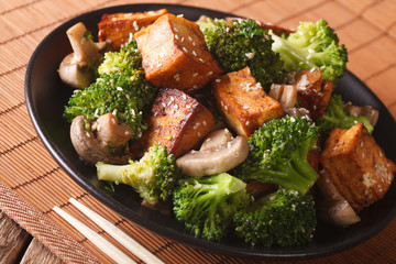 fast fried tofu with broccoli, mushrooms and sesame close-up. horizontal
