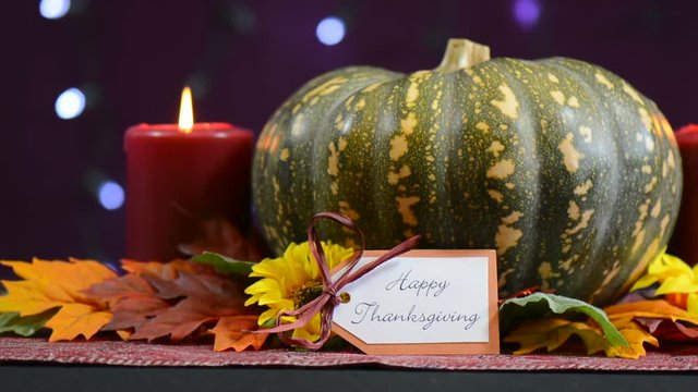 Happy Thanksgiving pumpkin centerpiece with candles against a bokeh fairy lights background, pan right.