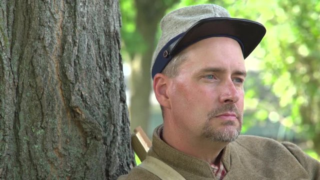 Confederate Civil War soldier leans on tree