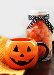 Halloween treats. Trick or treat. Sweets and candies in the cup. Pumpkin wreath background. Scary halloween. 