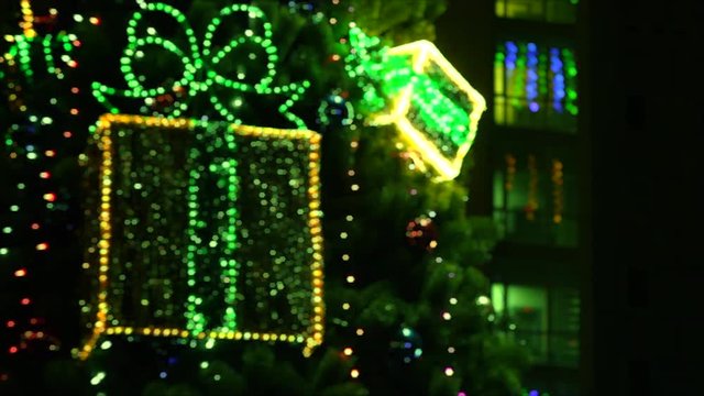 Shimmering boxes with gifts hanging on a Christmas tree. Windows of the house decorated with garlands. Hexagonal bokeh.