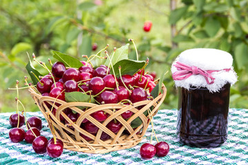 Basket of cherries and cherry jam jar on  background of cherry tree