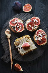 Bruschetta with figs, cheese and honey on a wooden serving board