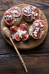 Bruschetta with figs, cheese and honey, rustic wooden setting