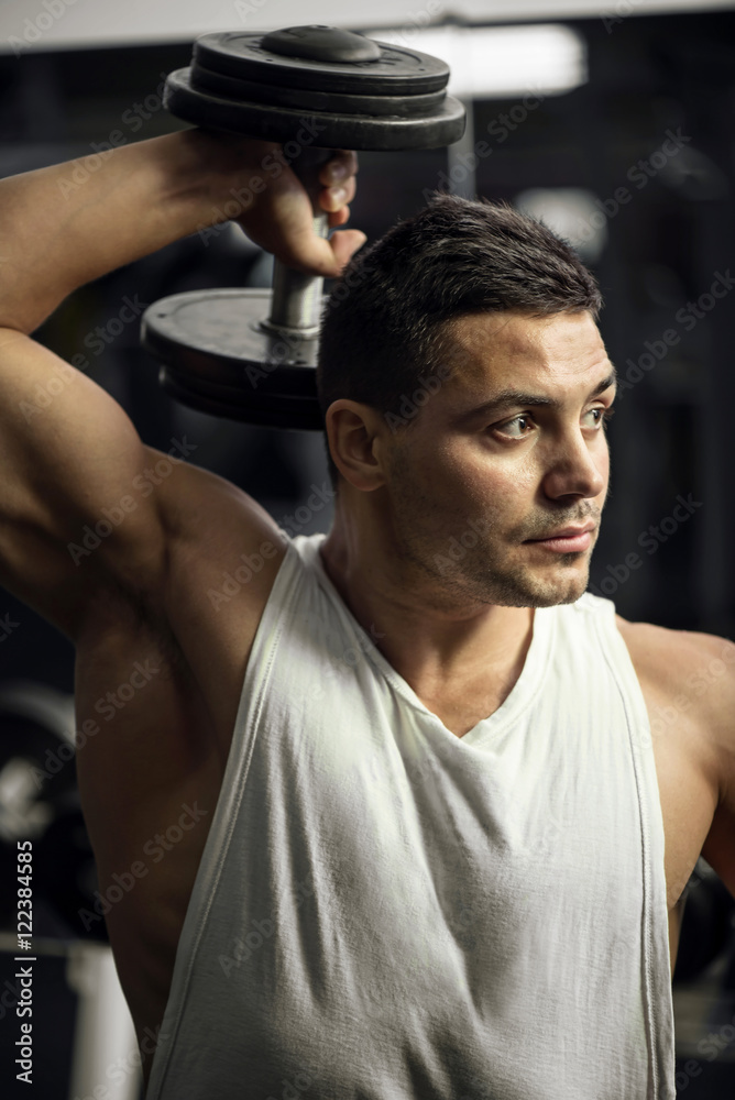 Wall mural Nice strong sportsman lifting a dumbbell