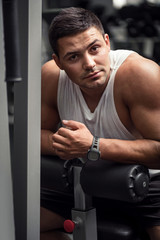 Fototapeta na wymiar Handsome brunette man leaning on a gym apparatus