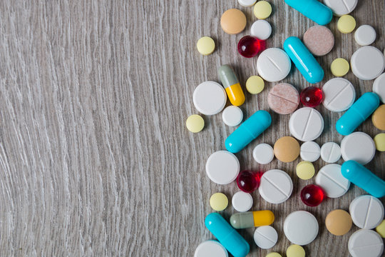 lot of colorful medication and pills from above on grey wooden background. Copy space. Top view, frame. Painkillers, tablets, generic , drugs.