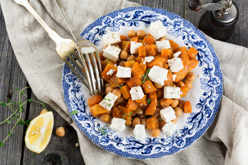 Salad of pumpkin, chickpeas and feta cheese on the old wooden background. Selective focus.