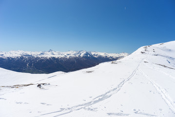 Wide angle view of a ski resort in the distance with elegant mountain peaks arising from the alpine arc in winter season. Torino Province on Italy France border.