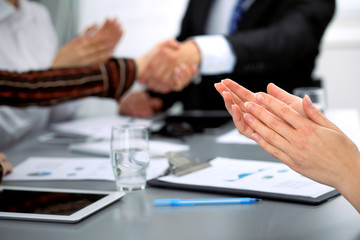 Close up of female applause while business people shaking hands at meeting