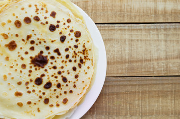Background with a pile of fresh homemade crepes. Thin pancakes on wooden background