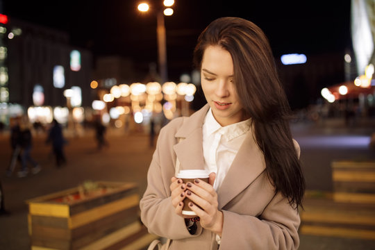 Portrait of woman in night city keep coffee cup