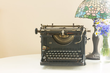 black vintage typewriter with retro lamp, copy space on wall