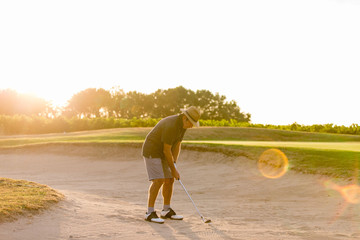 Senior Male Golfer Playing Bunker Shot On Golf Course