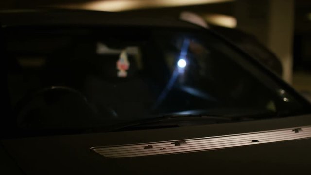  Blurred background of thief searching a car with a flashlight for valuables at night