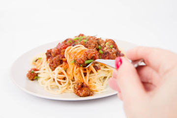 Spaghetti bolognese being eaten with a fork held by a woman's hand