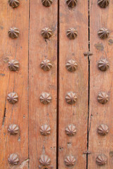 Part of the old wooden gate decorated with metal elements.