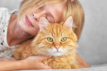 Attractive little girl with red fluffy cat on sofa in room
