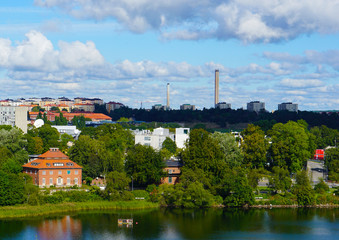 Landscape near the river. Spring, summer weather. Cloudy blue sky. Green trees.