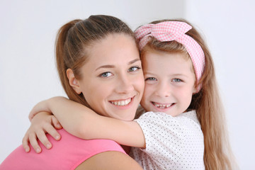Cute girl with mother on light background