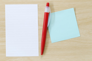 Note paper and red pen placed on wooden floor.