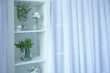 Beautiful flowers in glass vases on white shelf
