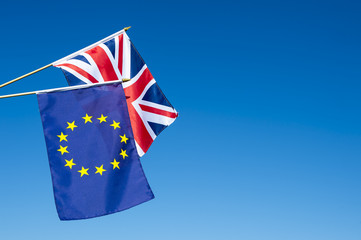 European Union and British Union Jack flag flying in front of bright blue sky in preparation for...