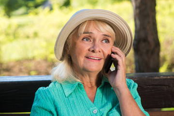 Senior woman on the phone. Mature lady in a hat. Stay in touch with relatives. Cheap calls abroad.