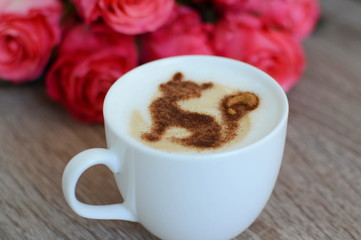 cup of cappuccino and yummy croissant with roses on the table