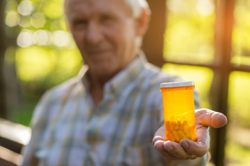 Male hand holds pill bottle. Medicine container of orange color. Best cure against pain. Science helps to save health.