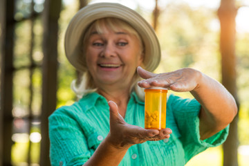 Woman with pill bottle smiling. Lady holding medicine. New vitamin formula. Drug that strengthens immunity.