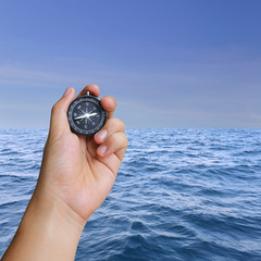 Hand of man holding a compass and view sea.