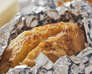 jacket potatoes with provola cheese wrapped in an aluminium foil on a slate plate