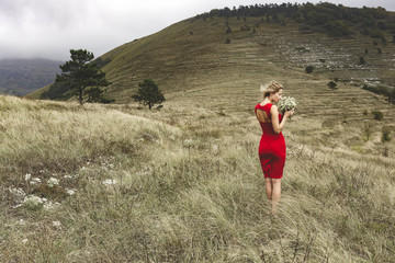 Fototapeta na wymiar Woman in red dress, bouquet, mountains