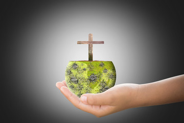 World arid and cross in yong hand. Cross representative of God that came to save the world.