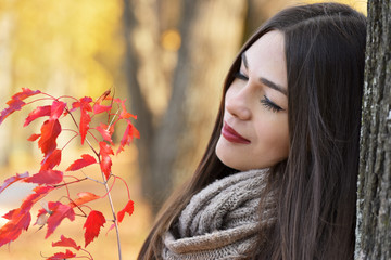 Naklejka premium Girl with a branch of a tree with red leaves in autumn park