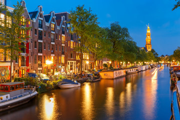 Night city view of Amsterdam canal Prinsengracht with houseboats and Westerkerk church, Holland, Netherlands.